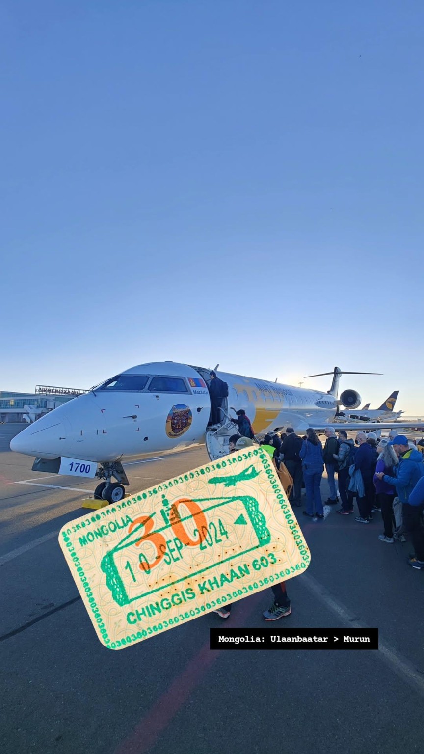 A Mongolia flight ticket held in front of passengers boarding an aircraft.